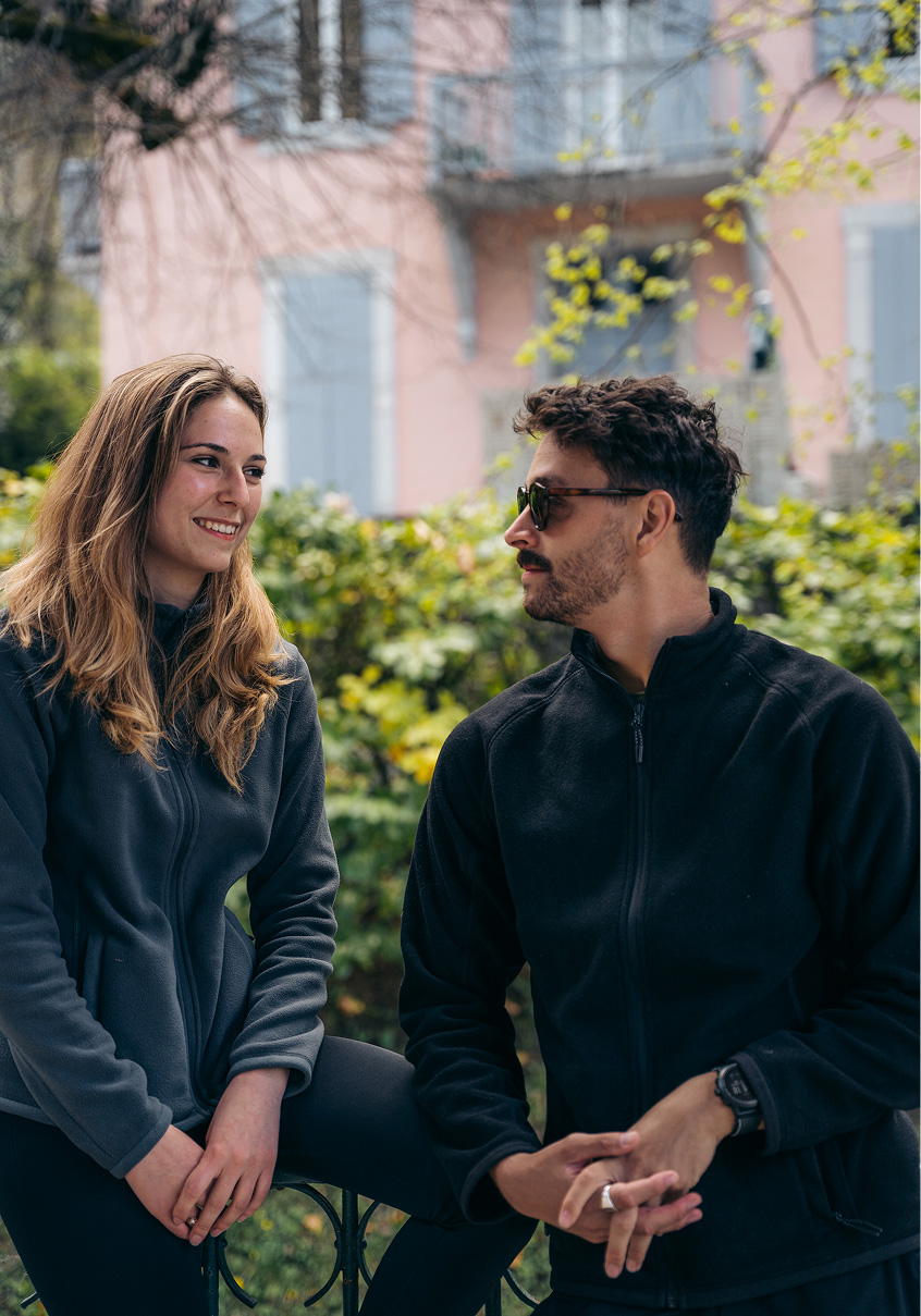 A woman and a man in dark fleece jackets talking outdoors.